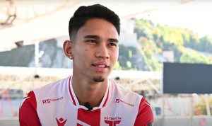 Marselino Ferdinan saat wawancara, mengenakan jersey klub AS Trenčín merah putih dengan logo RS Technology.