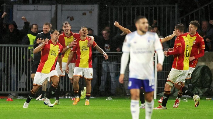 Go-Ahead-Eagles-Rayakan-Comeback-Aston-Villa-Dean-James.jpeg Pemain Go Ahead Eagles dengan seragam merah-kuning merayakan gol dengan ekspresi gembira di lapangan yang basah, sementara pemain lawan terlihat kecewa.