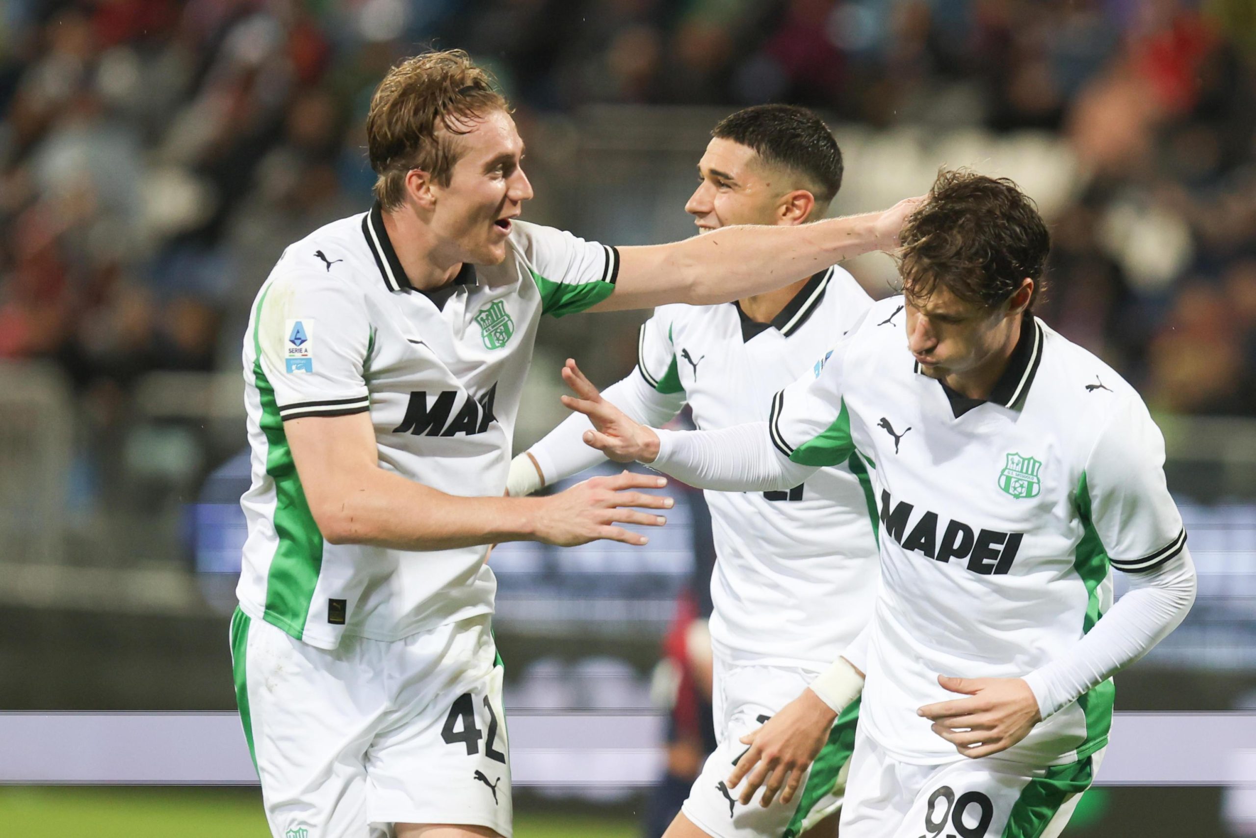 Sassuolo-Pemain-Rayakan-Gol-Jay-Idzes-Cagliari-Bungkam.jpeg Tiga pemain Sassuolo (seragam putih-hijau) merayakan gol atau momen penting dengan ekspresi gembira dan interaksi dekat.