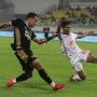 Pemain Dewa United (seragam hitam-emas) berduel ketat dengan pemain lawan (seragam putih-merah) di tengah lapangan yang basah.
