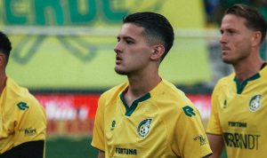 Justin Hubner, mengenakan jersey kuning Fortuna Sittard, di lapangan sepak bola bersama rekan satu timnya.