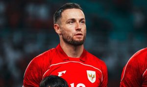 Pemain Timnas Indonesia Marc Klok berseragam merah dengan lambang Garuda di dada, memiliki janggut tipis dan menatap ke samping dengan ekspresi serius.