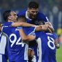 Pemain Persib Bandung dengan seragam biru merayakan gol bersama di lapangan sepak bola, saling berpelukan erat.