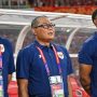 Tiga staf atau ofisial tim nasional sepak bola Indonesia mengenakan kaos polo biru gelap dengan logo Garuda, berdiri di tepi lapangan, terlihat fokus mengamati pertandingan atau persiapan tim.