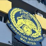 logo-persatuan-bolasepak-malaysia-fam.jpeg Logo resmi Persatuan Bolasepak Malaysia (FAM) di fasad kantor dengan lambang harimau dan bola, berwarna biru tua dan emas.