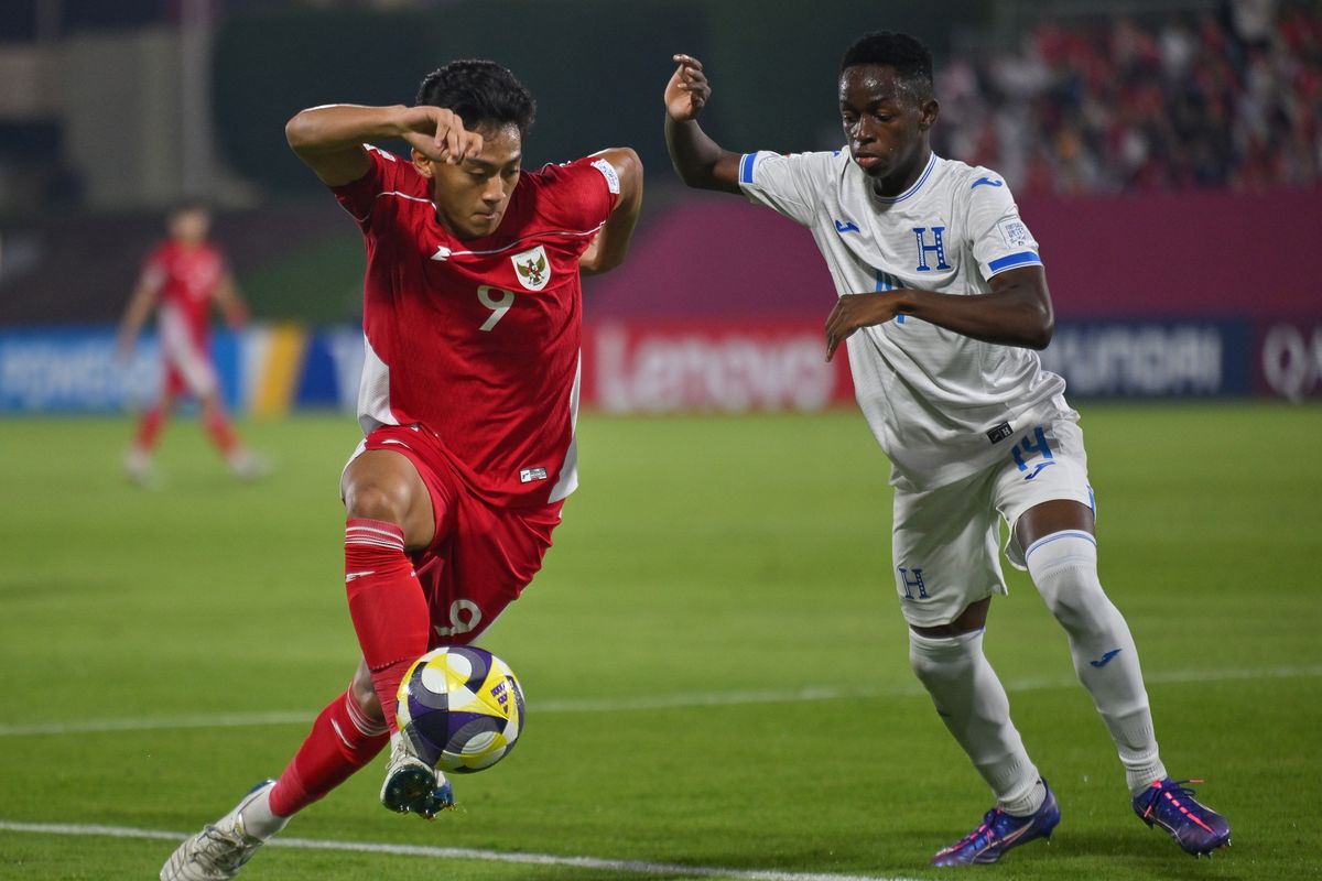 Pelatih Bima Sakti memberikan instruksi intensif kepada para pemain Timnas Indonesia U-17 yang berkumpul dalam formasi melingkar (huddle) di lapangan.