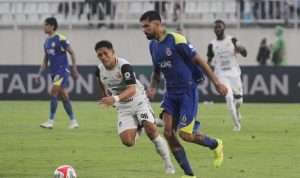 persija-jakarta-tumbangkan-arema-fc-comeback-kanjuruhan.jpg Pemain Persija Jakarta (jersey putih-oranye, nomor 98) berduel lari dengan pemain Arema FC (jersey biru, nomor 6) saat memperebutkan bola di lapangan hijau.