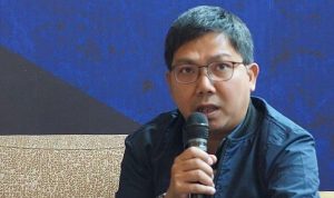 Bung-Towel-Tommy-Welly-Dukung-Keputusan-PSSI.jpg Pengamat sepak bola Indonesia, Bung Towel (Tommy Welly), berkacamata dan mengenakan jaket biru, sedang berbicara melalui mikrofon dalam sebuah konferensi pers atau wawancara.