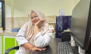 Potret Icha Kristy, seorang analis kesehatan, dengan latar belakang lingkungan laboratorium atau fasilitas kesehatan.