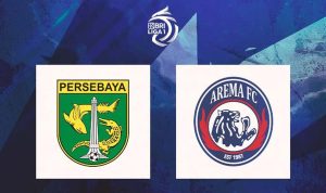 Duel udara intens antara pemain Persebaya (hijau) dan pemain Arema (biru) di tengah lapangan dalam pertandingan sepak bola.