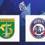 Duel udara intens antara pemain Persebaya (hijau) dan pemain Arema (biru) di tengah lapangan dalam pertandingan sepak bola.