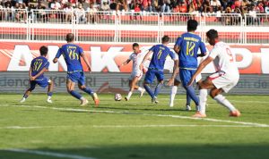 Momen intens pertandingan sepak bola antara Malut United dan Arema FC dengan pemain dari kedua tim sedang berebut bola di lapangan.