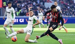 Pemain Jay Idzes (kaos putih hijau-hitam) melakukan tekel krusial untuk menghentikan laju pemain AC Milan (kaos merah-hitam) dalam pertandingan yang berakhir 2-2.