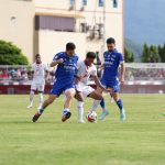 Kemenangan-Beruntun-Persib-Terhenti-Malut-United-Ternate.webp Tiga pemain Persib Bandung (jersey biru) berduel sengit melawan pemain Malut United (jersey putih-merah) dalam perebutan bola di tengah lapangan hijau.