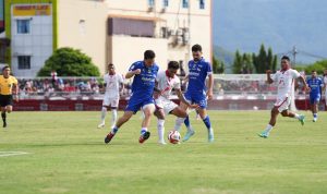 Tiga pemain Persib Bandung (jersey biru) berduel sengit melawan pemain Malut United (jersey putih-merah) dalam perebutan bola di tengah lapangan hijau.