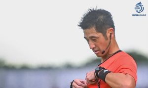Wasit sedang memegang kartu di tengah pertandingan sepak bola dengan logo I.League sebagai penyelenggara kompetisi.