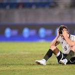 Pemain Indonesia U-22 (nomor 9) duduk di lapangan rumput dengan tangan memegangi kepala, menunjukkan kekecewaan atau tekanan tinggi dalam pertandingan krusial.