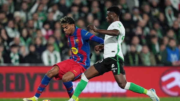 Lamine Yamal dari Barcelona sedang mendribel bola melewati pemain Racing Santander dalam pertandingan Racing Santander vs Barcelona.