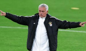 Jose Mourinho mengenakan jaket latihan Benfica memberikan instruksi taktis di pinggir lapangan dalam laga krusial melawan Real Madrid.
