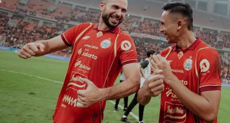Selebrasi ceria dua pemain Persija Jakarta di tengah lapangan setelah mencetak gol, menunjukkan kekompakan tim menjelang laga tandang.