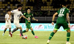 Pemain Persebaya sedang berebut bola dengan pemain PSM Makassar di tengah guyuran hujan dalam laga sengit Liga 1.