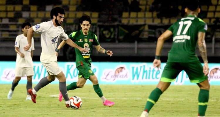 Pemain Persebaya sedang berebut bola dengan pemain PSM Makassar di tengah guyuran hujan dalam laga sengit Liga 1.