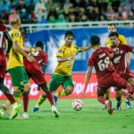 Pemain Persebaya sedang menggiring bola melewati hadangan ketat pemain PSM Makassar dalam pertandingan Liga 1.