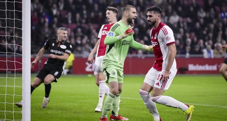 Kiper Maarten Paes mengenakan jersey hijau neon sedang memberikan instruksi dengan tegas kepada lini pertahanan timnya saat pertandingan berlangsung.