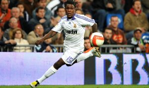 Royston Drenthe, mantan wonderkid Real Madrid, sedang berlari kencang menggiring bola dengan jersey putih legendaris Los Blancos di Santiago Bernabeu.