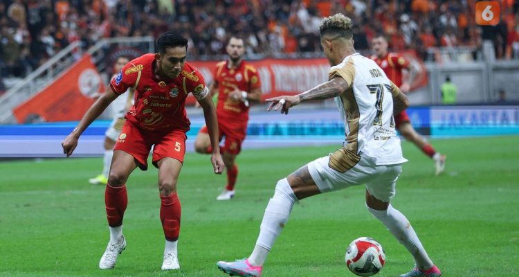 Kapten Persija Jakarta, Rizky Ridho, sedang membayangi pergerakan pemain Dewa United dalam pertandingan Liga 1 di JIS.