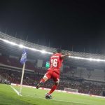 Dony Tri Pamungkas mengambil tendangan sudut dalam pertandingan Timnas Indonesia di stadion megah, dengan hakim garis melihat dari dekat.