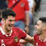 Elkan Baggott dan Jordi Amat, dua pemain Timnas Indonesia dengan jersey merah, tertawa gembira saat merayakan kemenangan di lapangan.