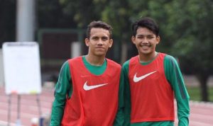Dua pemain Timnas Indonesia, Egy Maulana Vikri dan rekan setimnya, mengenakan jersey latihan hijau dengan rompi merah Nike di pinggir lapangan lari.
