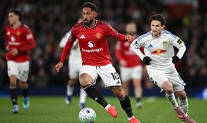 Pemain Manchester United bernomor punggung 10 sedang menggiring bola dibayangi pemain Leeds United dalam pertandingan di Old Trafford.