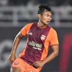 Pemain Borneo FC sedang bertanding di lapangan mengenakan jersey oranye dan merah marun.