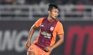 Pemain Borneo FC sedang bertanding di lapangan mengenakan jersey oranye dan merah marun.