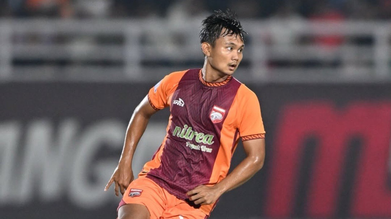 Pemain Borneo FC sedang bertanding di lapangan mengenakan jersey oranye dan merah marun.