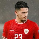 Pemain naturalisasi Timnas Indonesia Justin Hubner mengenakan jersey merah berlogo Garuda saat pertandingan di bawah guyuran hujan, sebagai representasi kebijakan PSSI.