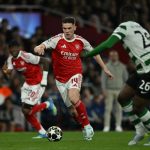 Pemain Arsenal nomor punggung 14 menggiring bola melewati pemain Sporting CP dalam pertandingan Liga Champions.