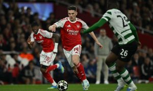 Pemain Arsenal nomor punggung 14 menggiring bola melewati pemain Sporting CP dalam pertandingan Liga Champions.