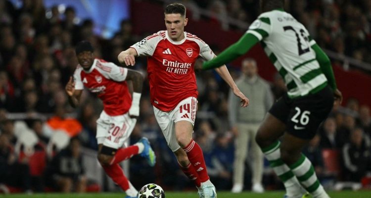 Pemain Arsenal nomor punggung 14 menggiring bola melewati pemain Sporting CP dalam pertandingan Liga Champions.