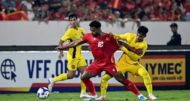 Pemain Timnas Vietnam nomor punggung 12 sedang berduel sengit memperebutkan bola dengan pemain Malaysia di Kualifikasi Piala Asia.