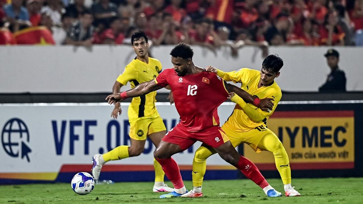 Pemain Timnas Vietnam nomor punggung 12 sedang berduel sengit memperebutkan bola dengan pemain Malaysia di Kualifikasi Piala Asia.