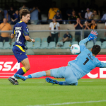 Emil Audero melakukan penyelamatan akrobatik dengan menepis bola saat berhadapan satu lawan satu dengan pemain lawan, memperlihatkan komitmennya untuk menghindarkan tim dari degradasi.