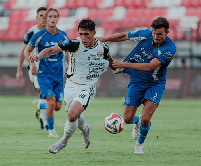 Duel sengit antara pemain Persija Jakarta dengan pemain lawan dalam perebutan bola di lapangan.