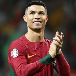 Pemain Sepakbola Cristiano Ronaldo mengenakan jersey Timnas Portugal sedang bertepuk tangan di lapangan hijau.