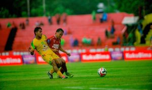Pemain Persebaya Surabaya dengan jersey kuning berebut bola sengit melawan pemain Semen Padang dalam pertandingan Super League yang berakhir dengan skor 7-0.