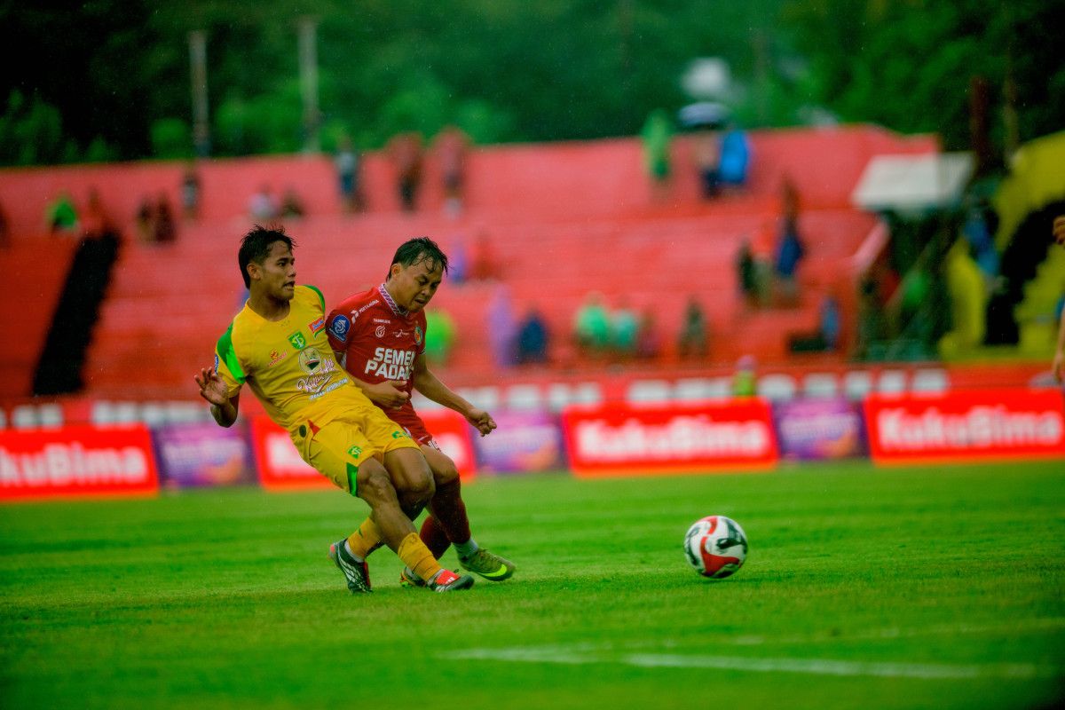 Pemain Persebaya Surabaya dengan jersey kuning berebut bola sengit melawan pemain Semen Padang dalam pertandingan Super League yang berakhir dengan skor 7-0.