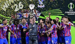 Pemain Crystal Palace merayakan gelar juara UEFA Conference League sambil mengangkat trofi di atas panggung penuh konfeti.