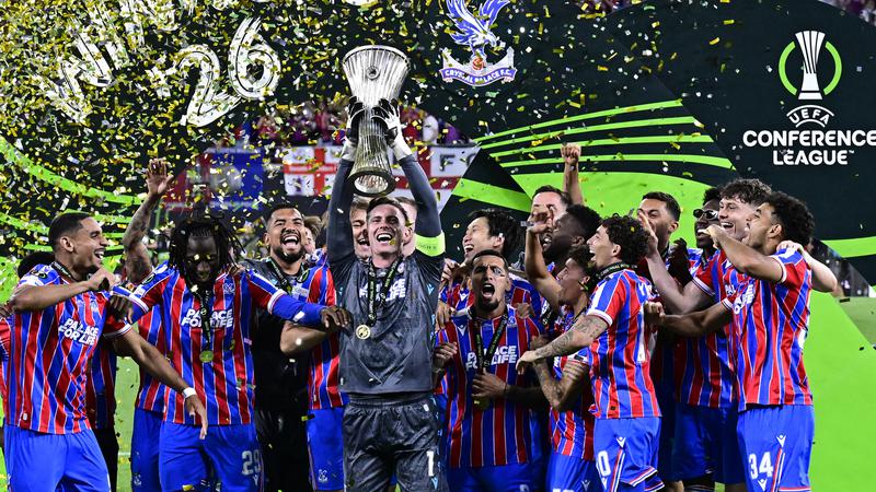 Pemain Crystal Palace merayakan gelar juara UEFA Conference League sambil mengangkat trofi di atas panggung penuh konfeti.